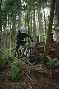 A cyclist wearing padded knee guards riding through a forest trail.