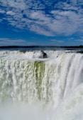 water falls under blue sky during daytime