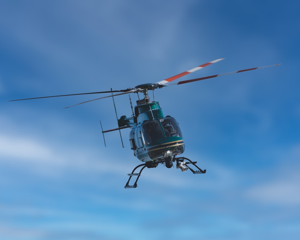 black and red helicopter flying under blue sky during daytime