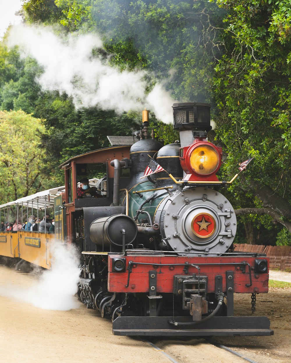 black and red train on rail tracks near green trees during daytime