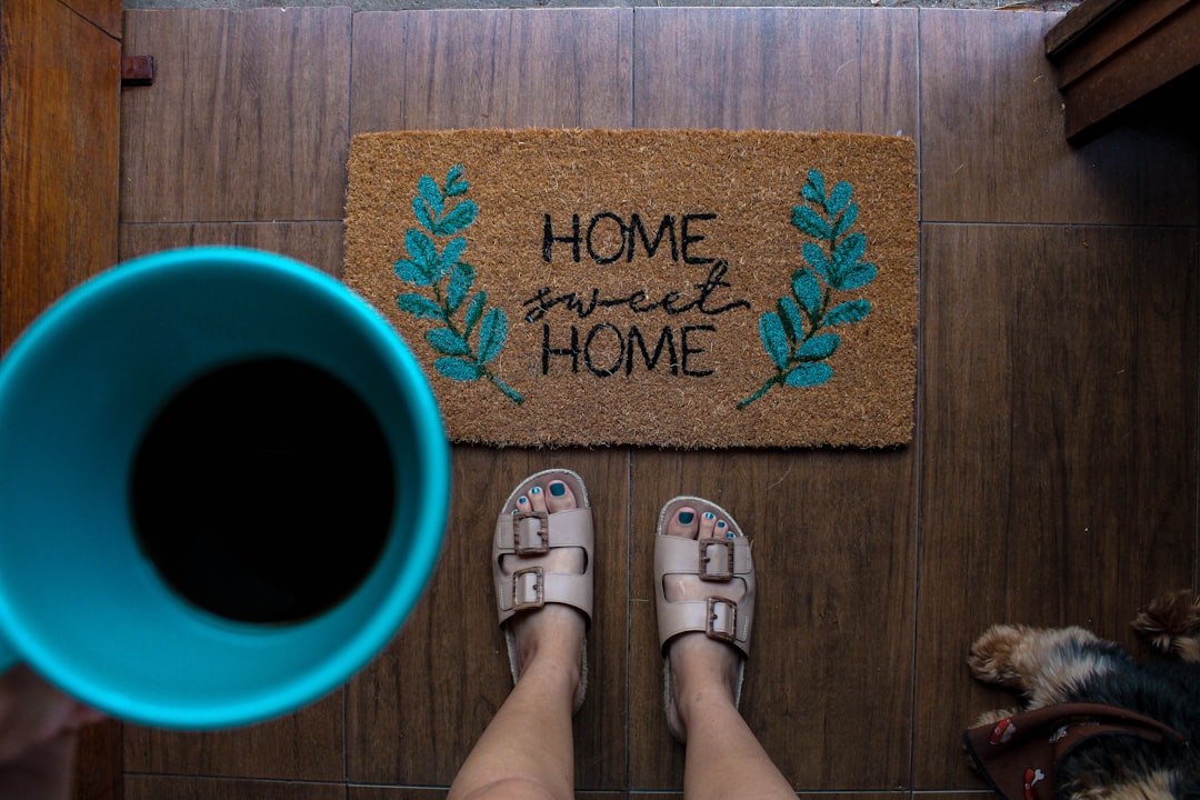  person in white leather sandals standing on brown wooden floor doormat