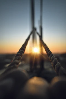 Close-up of ropes and sails bathed in soft terracotta light, capturing the texture and warmth of the moment.