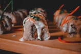 Artfully arranged sushi rolls with a variety of fillings and sauces on a wooden board.