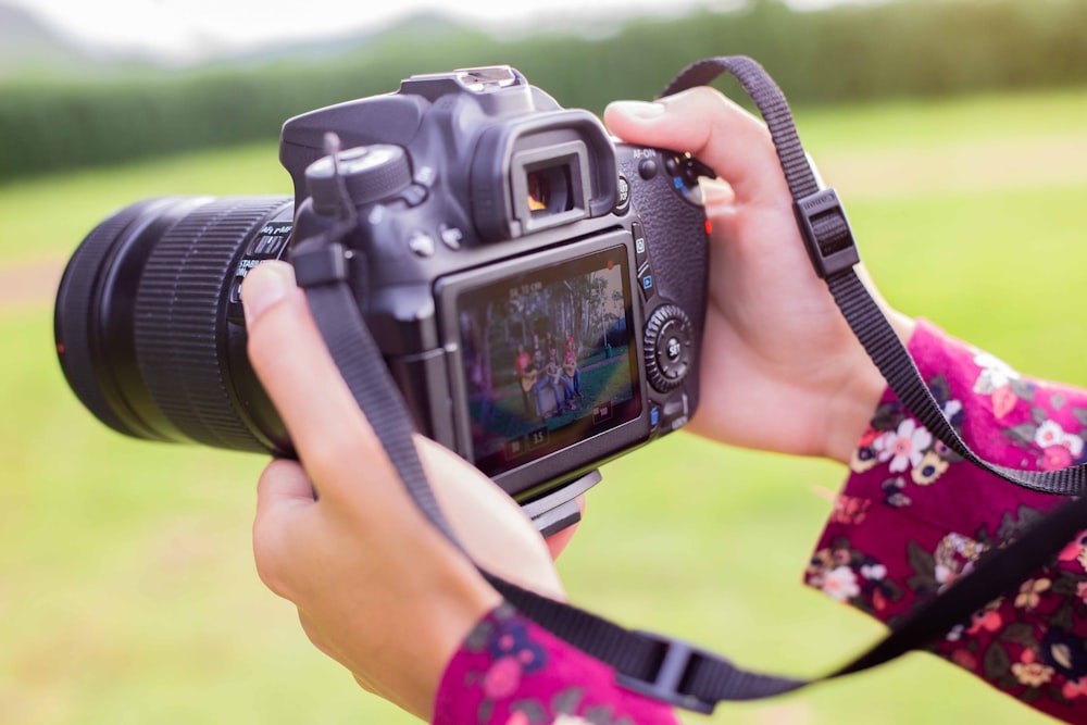 Persona sosteniendo una cámara DSLR negra