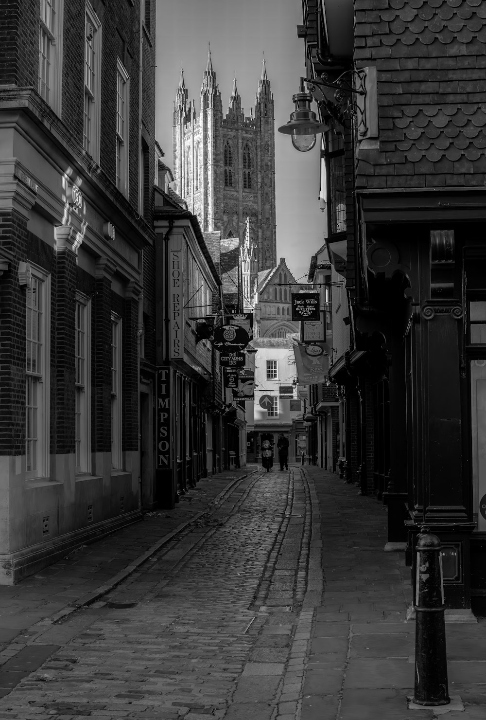 grayscale photo of a street in between buildings