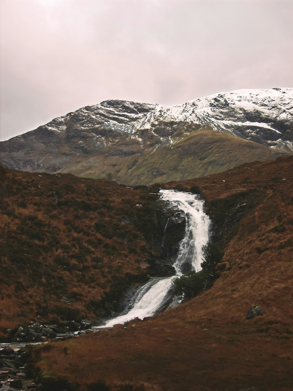 water falls on brown and green mountain