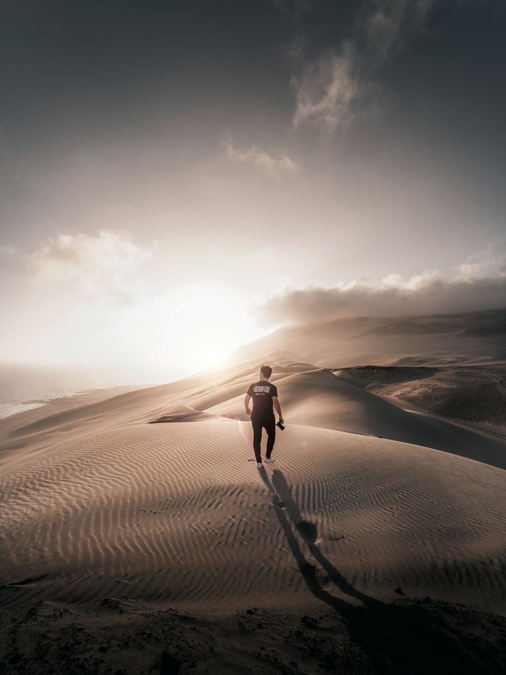 woman in black tank top and blue denim shorts standing on brown sand during daytime