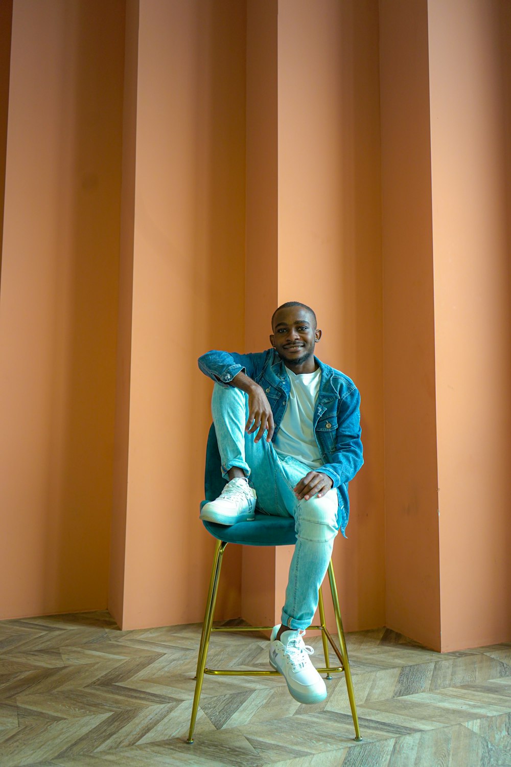 man in blue dress shirt and blue denim jeans sitting on green chair