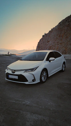A sleek white sedan parked by the beachside in Visakhapatnam at sunset.
