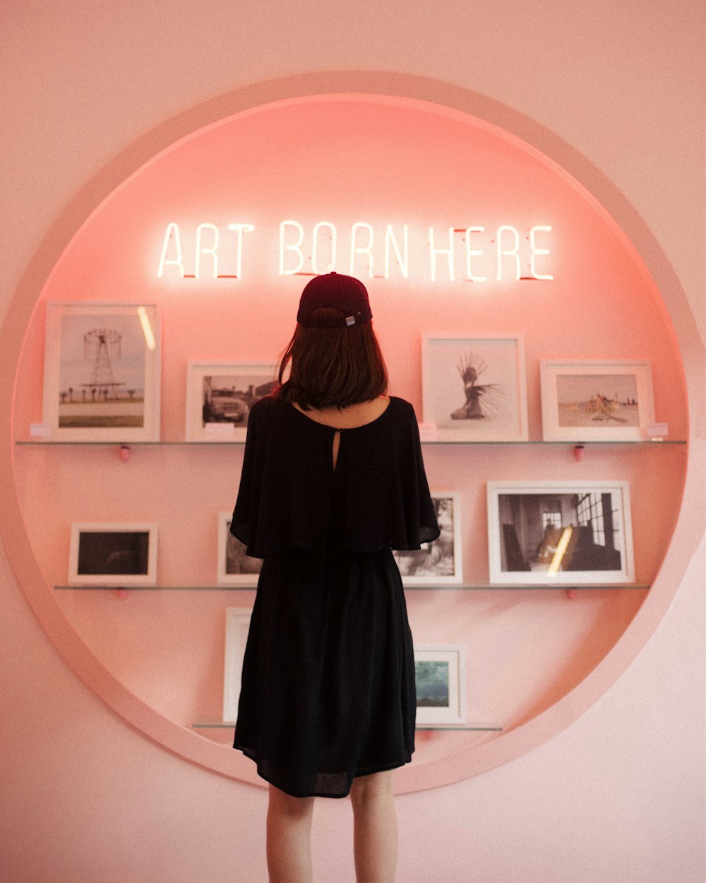 woman in black dress standing in front of white wooden shelf