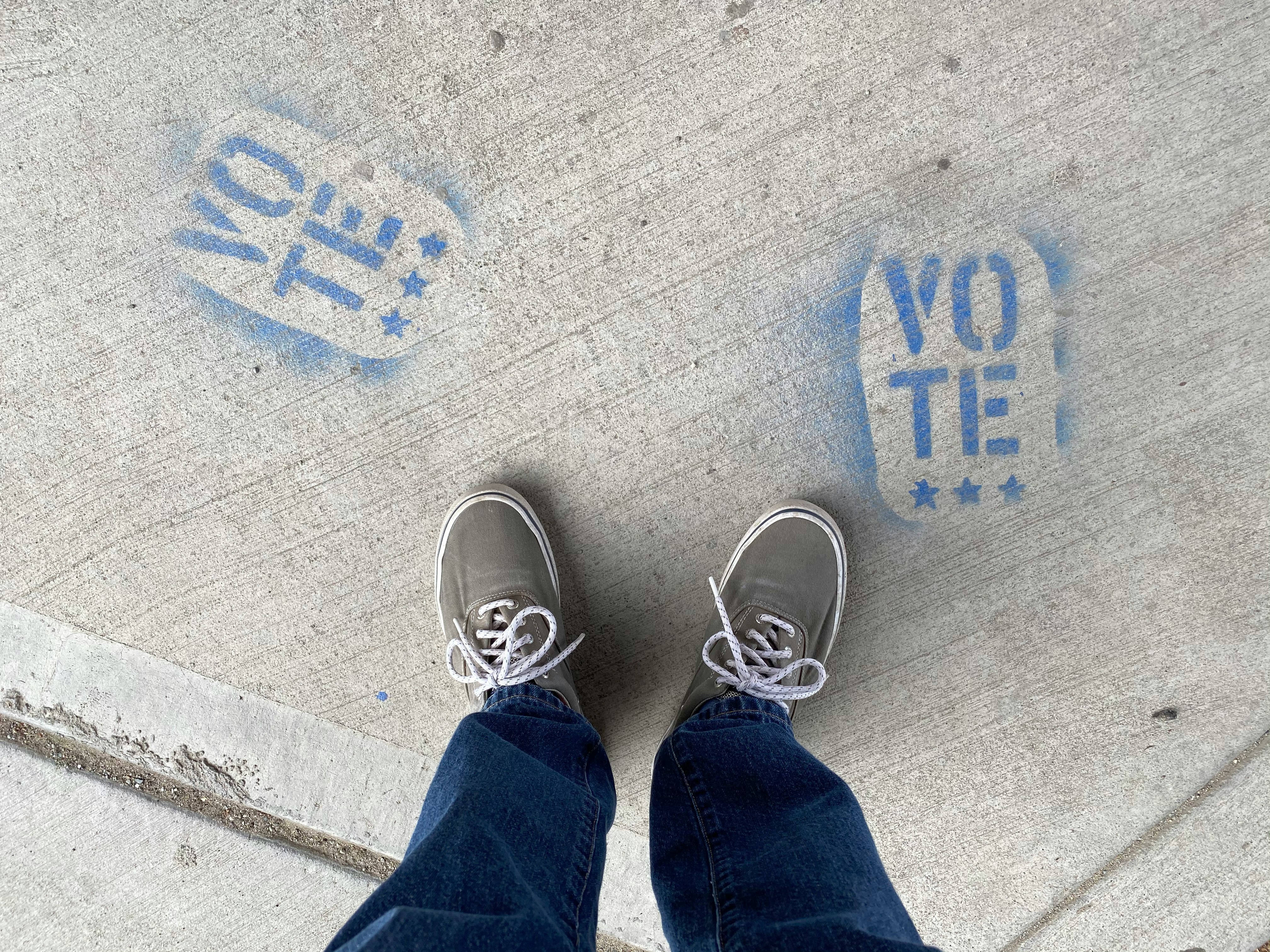 person in blue denim jeans and white sneakers standing on gray concrete floor