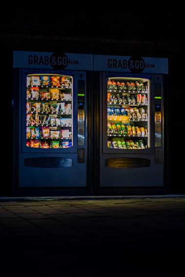 A sleek Go vending machine stocked with colorful healthy products inside a bustling university hallway.