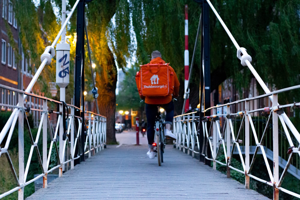 homme en veste rouge faisant du vélo sur le pont pendant la journée