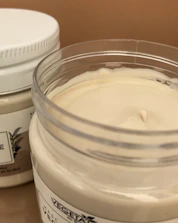 A jar of creamy moisturiser surrounded by warm rose-colored fabric folds.
