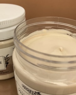 Moisturizer jars with creamy texture, placed on a soft towel near a window.