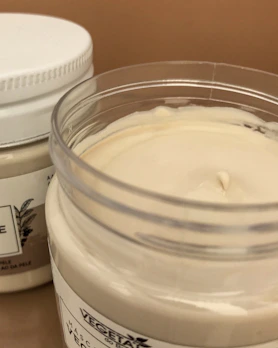 Moisturizer cream in an open jar surrounded by natural ingredients.