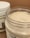 Two jars of cream or lotion with one open jar showing a smooth, creamy substance inside. The jars have white lids and label designs featuring text and botanical illustrations.