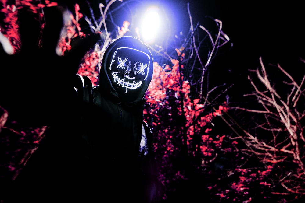 man in black and white hoodie standing under the tree with blue and white ball