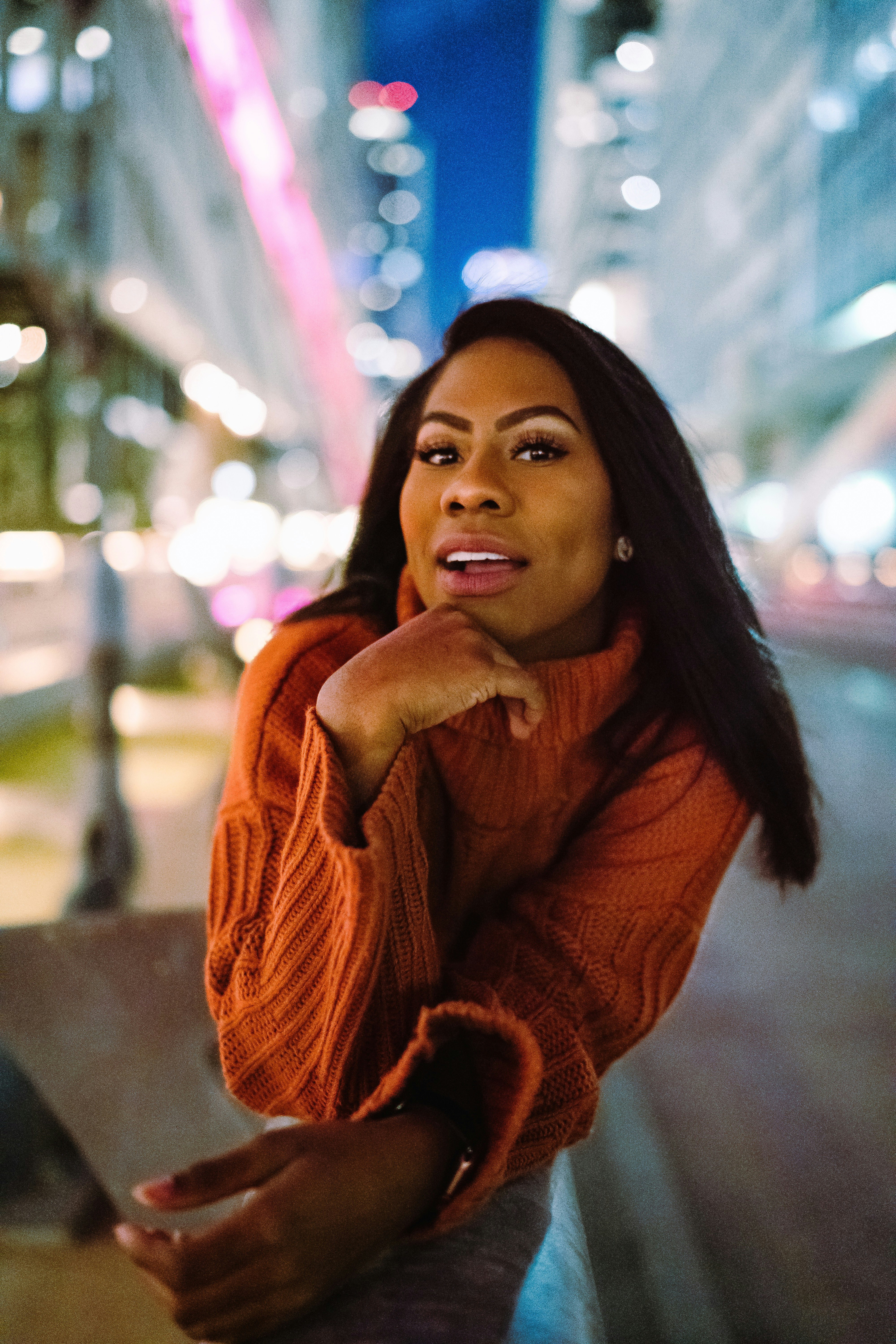 woman in brown scarf leaning on gray concrete wall during daytime