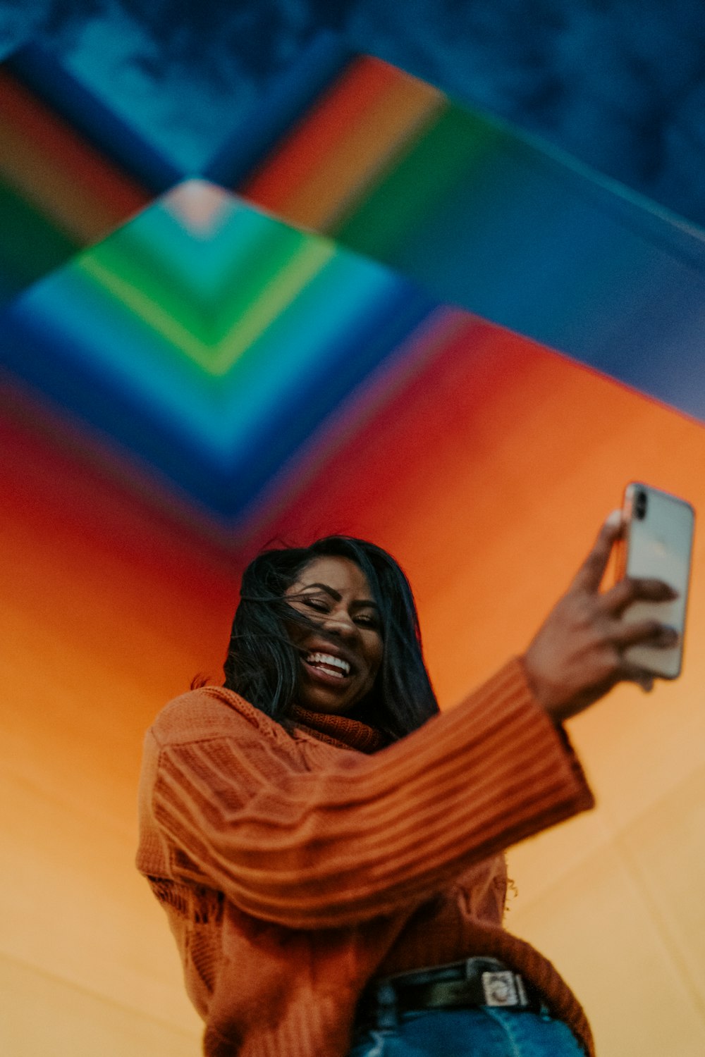 woman in brown jumper holding white smartphone