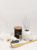 black and brown round container beside white ceramic vase