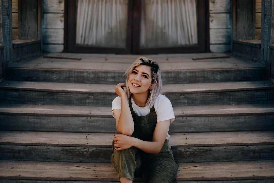 woman in white shirt and green pants sitting on stairs