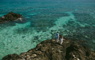 Happy couple enjoying a sunny terrace overlooking the turquoise sea in the Balearics.