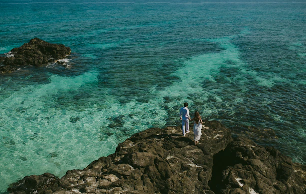 Happy couple enjoying a sunny terrace overlooking the turquoise sea in the Balearics.