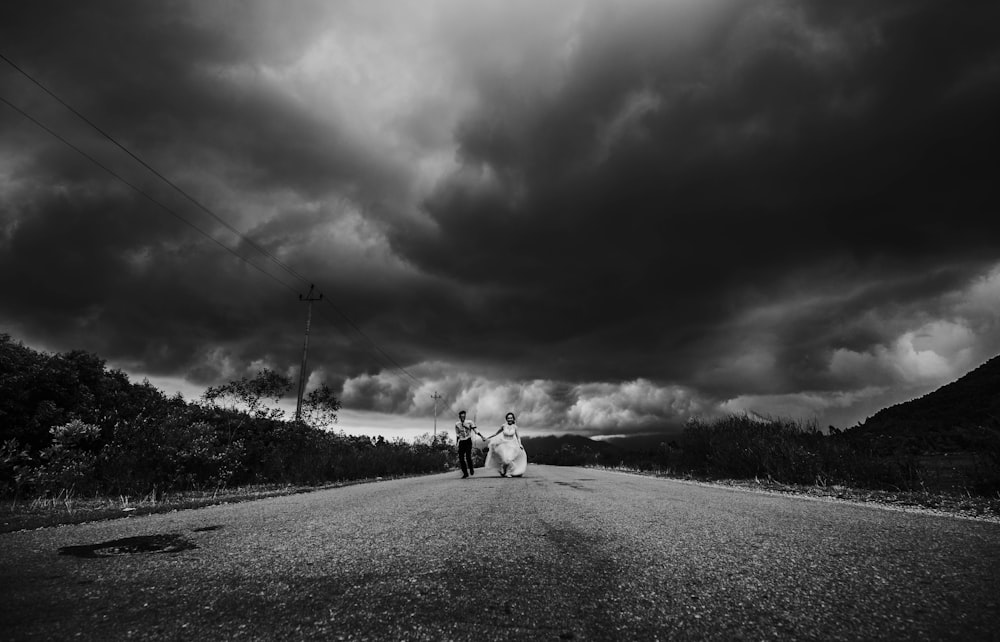 grayscale photo of 2 person walking on road