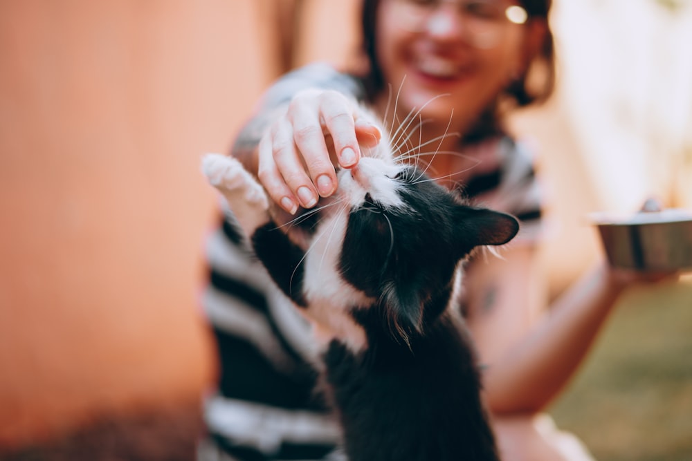 woman holding black and white cat