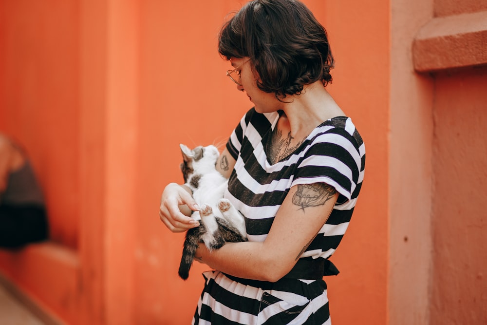 woman in black and white stripe shirt carrying white cat