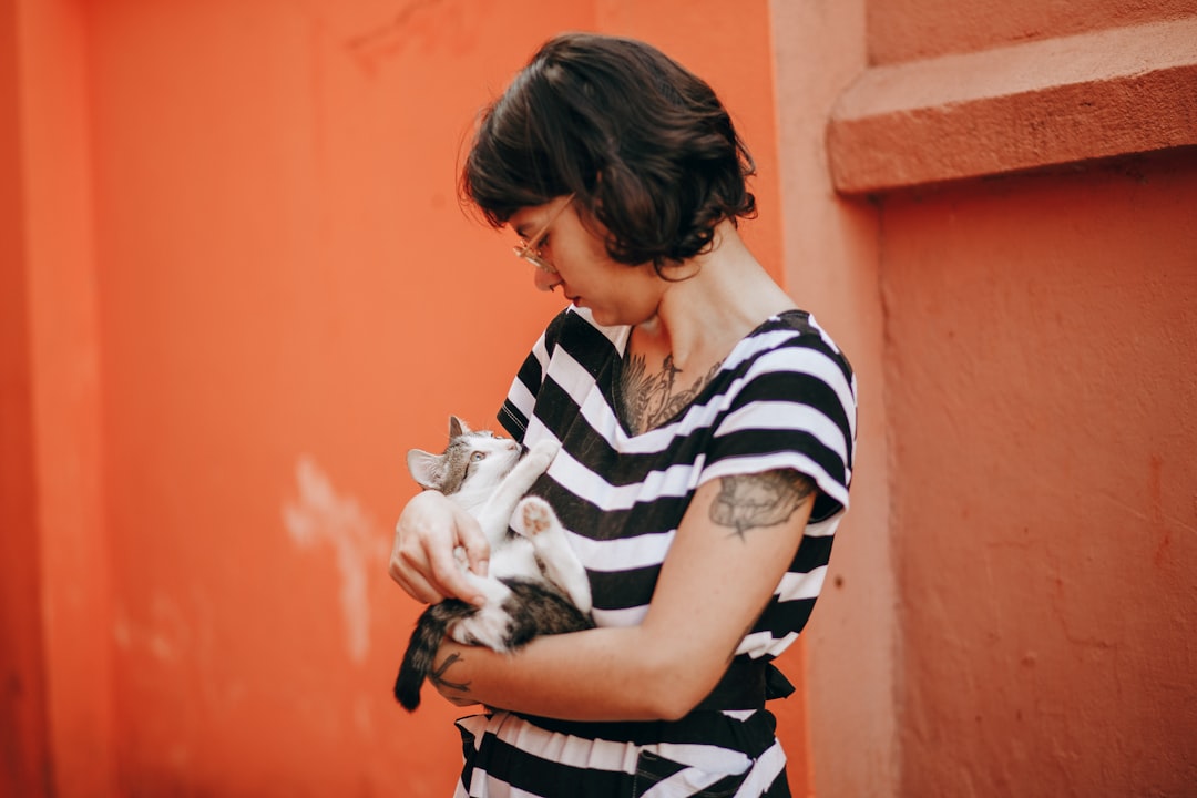 woman in black and white stripe shirt carrying white cat