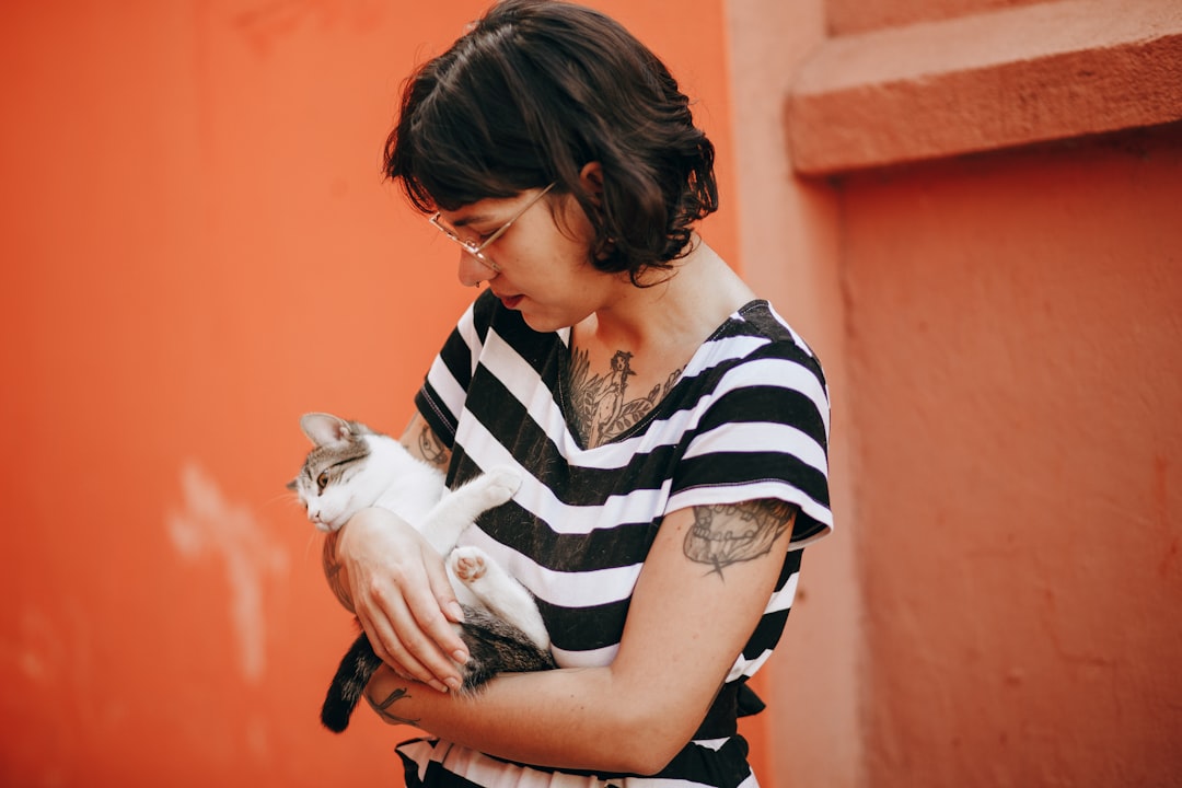 woman in black and white stripe shirt carrying white cat