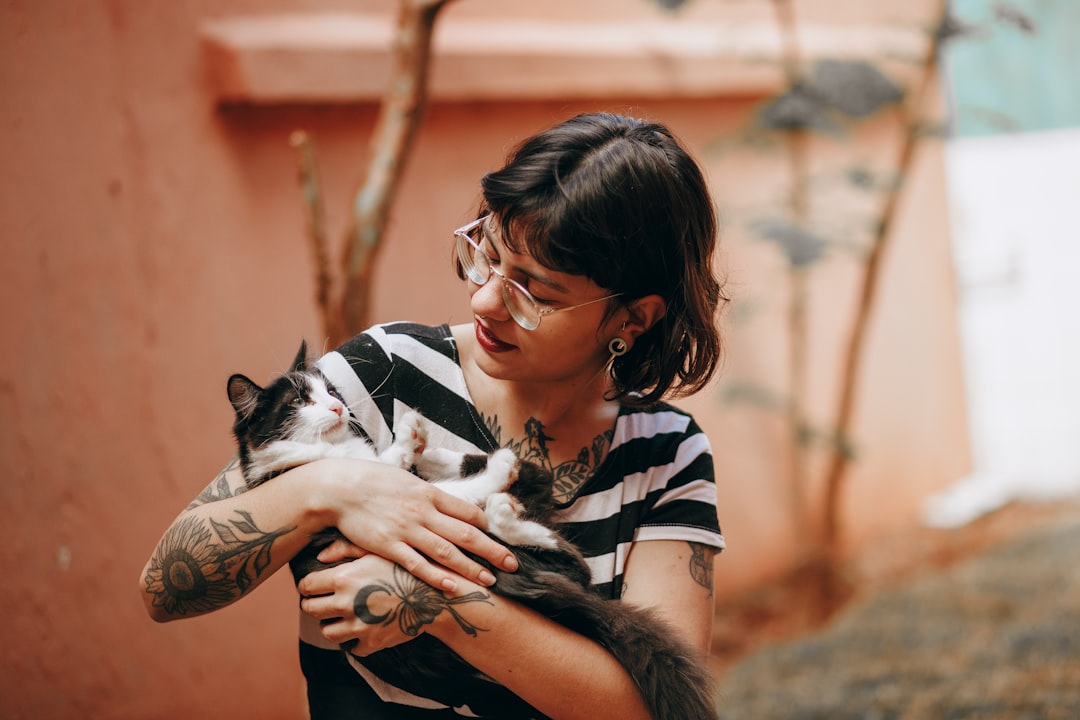 woman in black and white striped long sleeve shirt carrying white and black short coated puppy