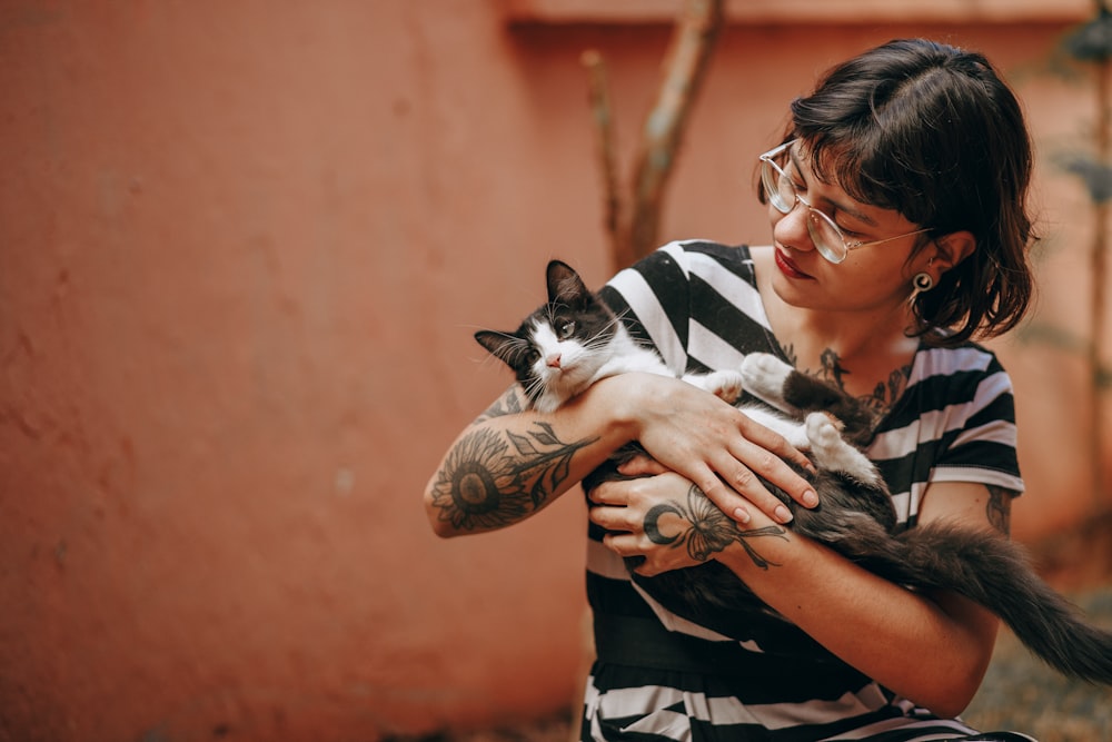 woman in black and white shirt carrying black and white cat