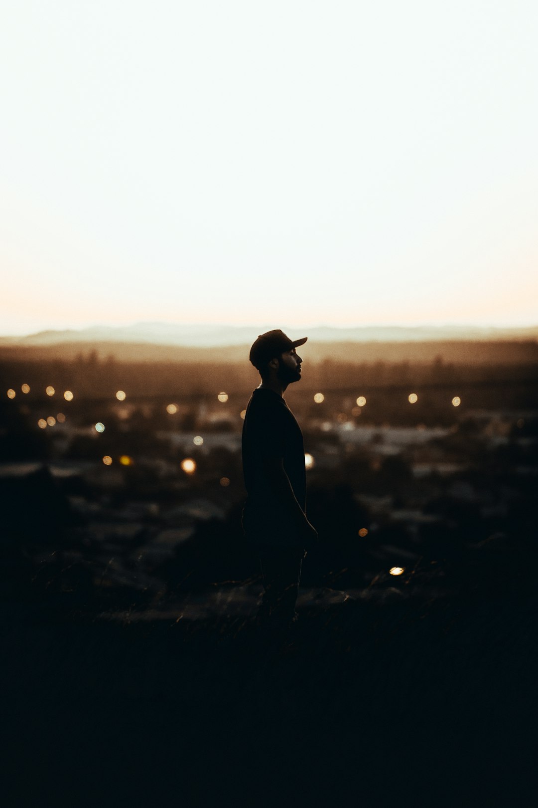 silhouette of man wearing hat standing on ground during sunset