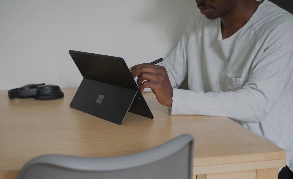 man in white shirt using black laptop computer