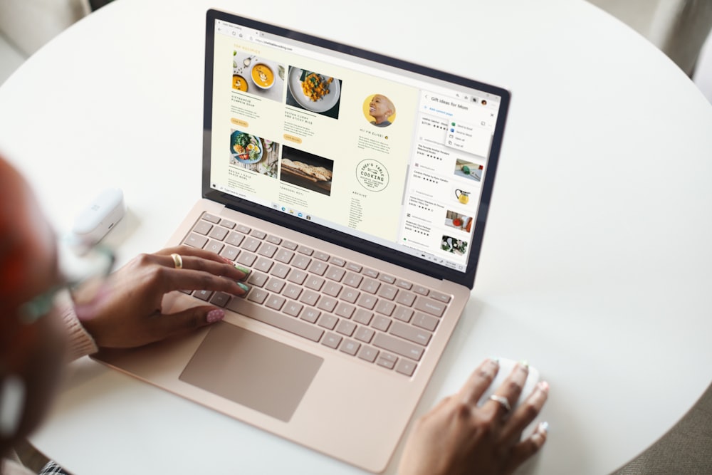 person using Surface laptop on white table