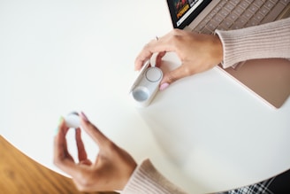 A close-up of hands testing a modern gadget on a clean white table.