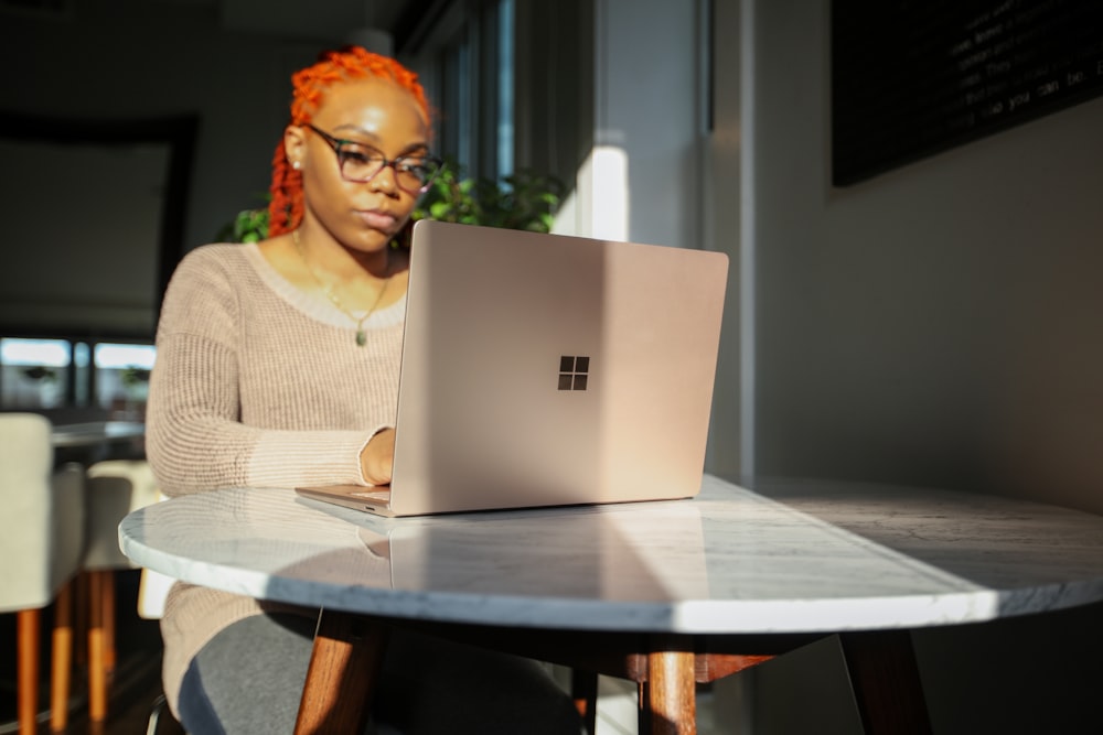 woman in beige knit sweater using Surface laptop