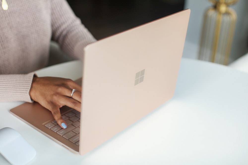 person in gray long sleeved shirt using Surface laptop