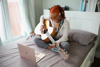 woman in white shirt playing acoustic guitar