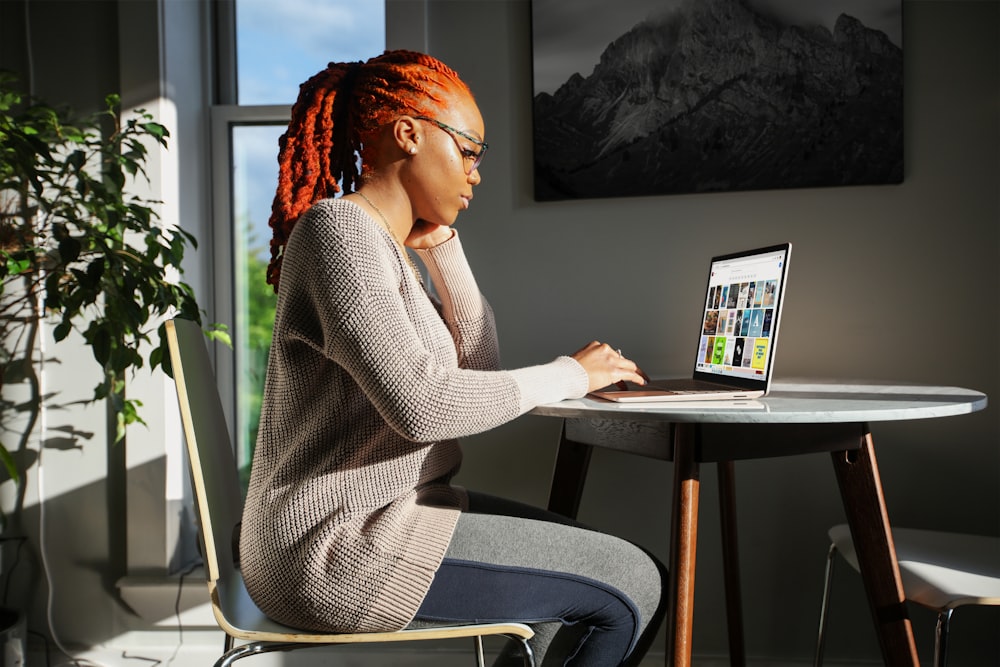 woman in gray sweater using Surface laptop