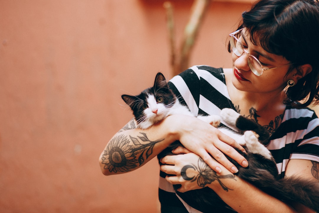 woman in black and white stripe shirt carrying black and white cat