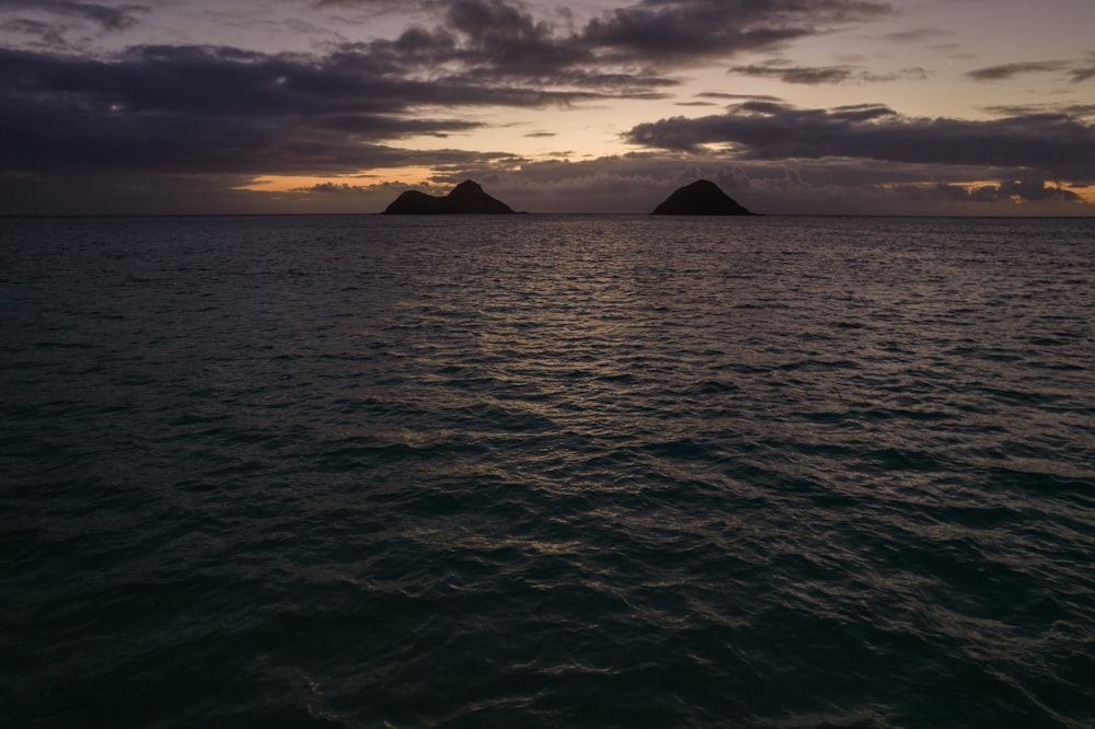 body of water near mountain during sunset