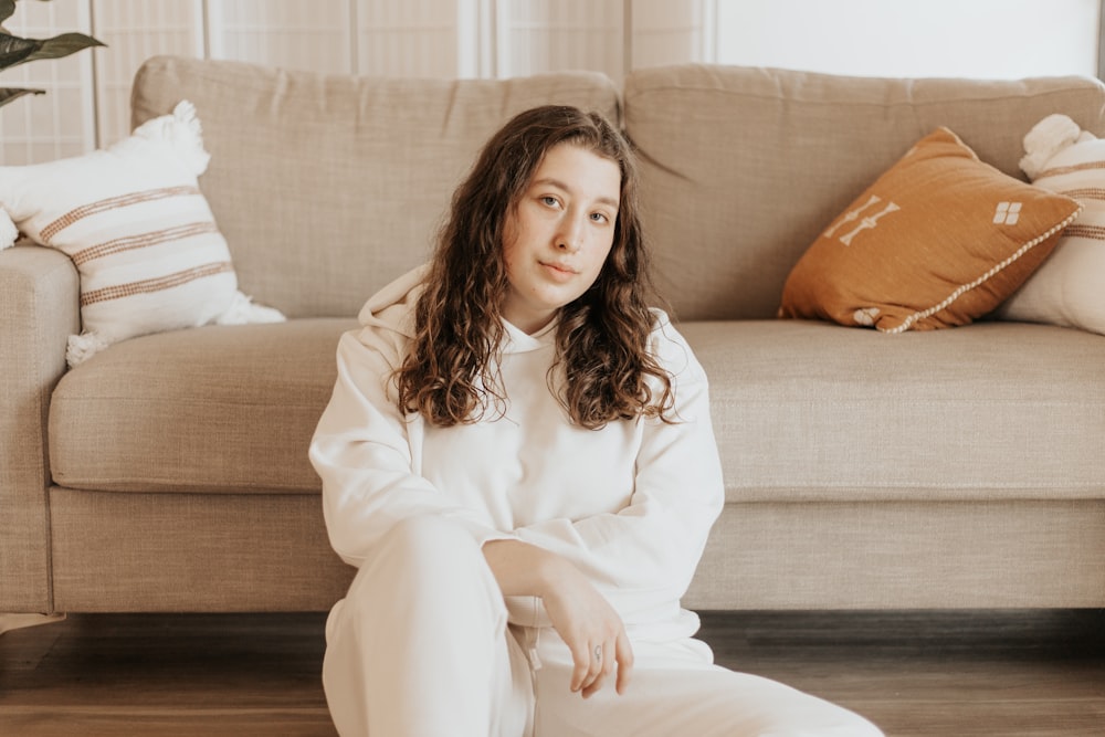 woman in white long sleeve shirt sitting on brown couch