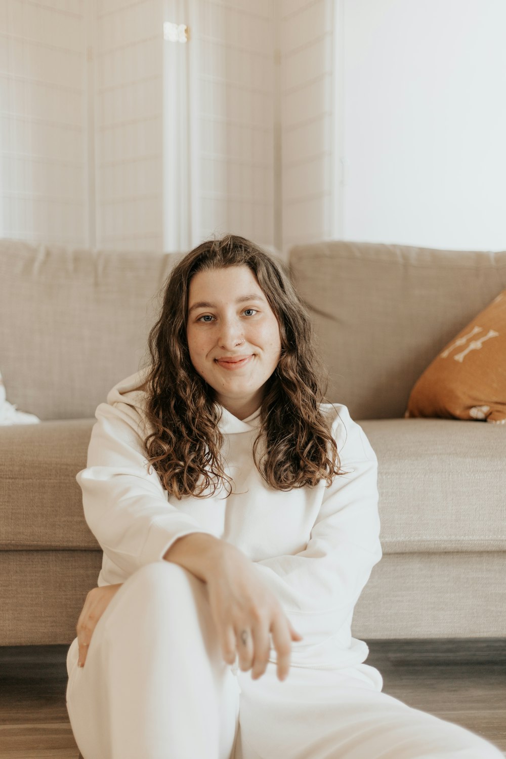 woman in white long sleeve shirt sitting on brown couch