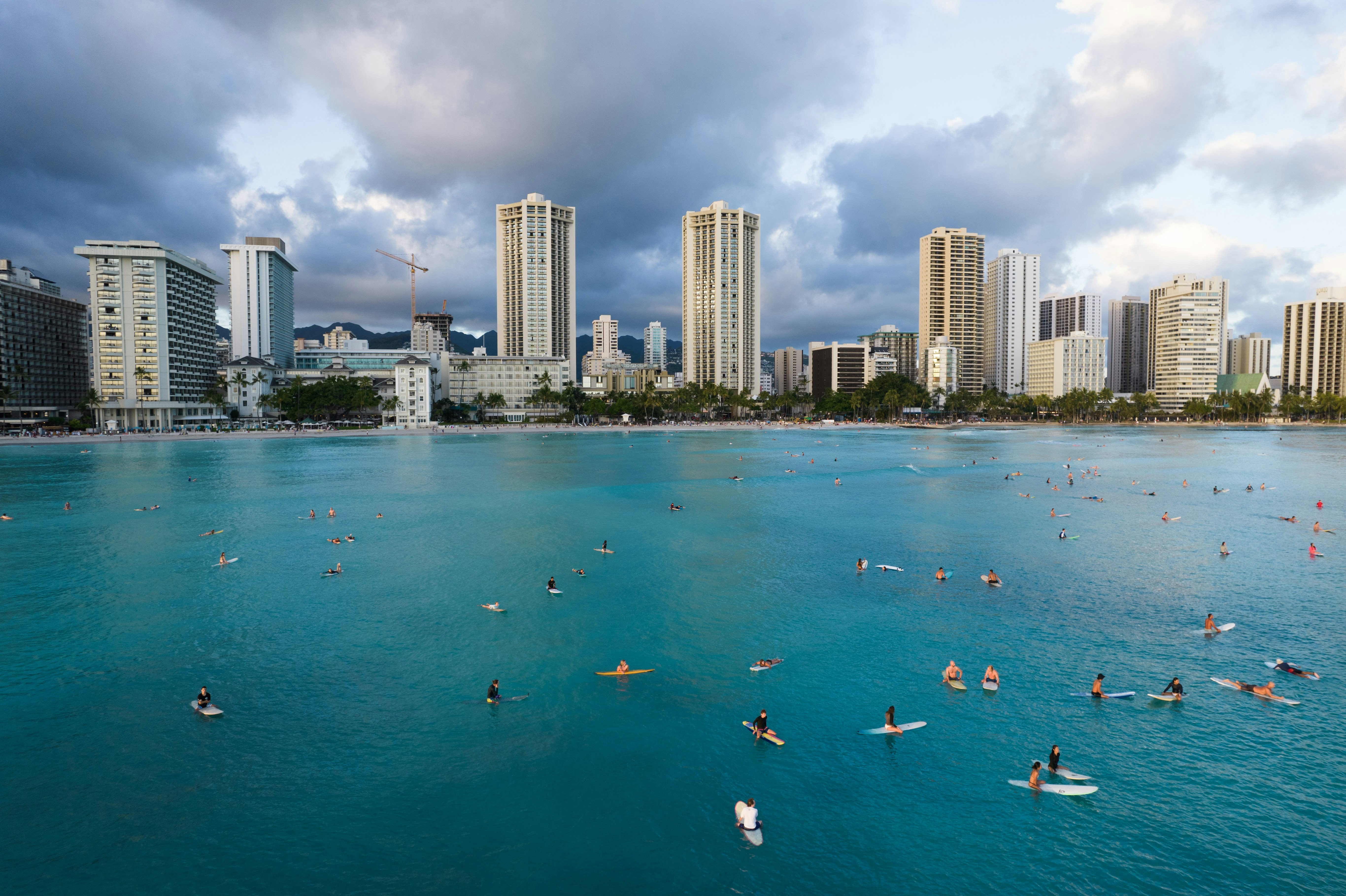 people swimming on beach near high rise buildings during daytime