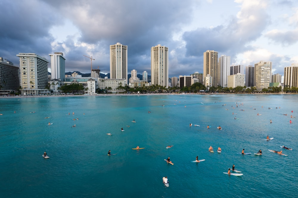 people swimming on beach near high rise buildings during daytime