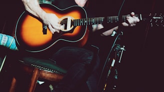 man in black tank top playing acoustic guitar